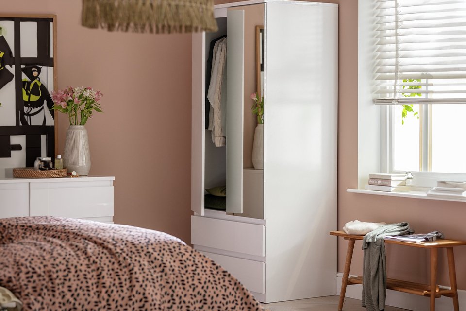 Pink bedroom with white mirrored wardrobe and clothing.